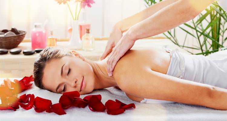 Frau erhält eine Massage mit Rosenblättern.
