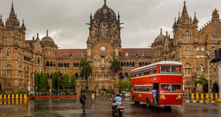 Chhatrapati Shivaji Terminus mit einem roten Doppeldeckerbus im Vordergrund.