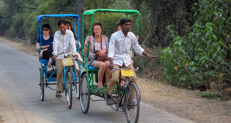 Zwei Rikschas mit Passagieren auf einer ländlichen Straße.