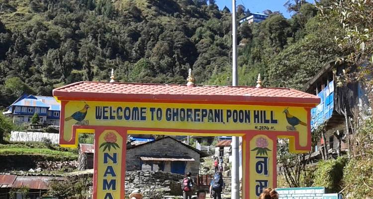 Toegangsbord van Ghorepani Poon Hill met omringende gebouwen.