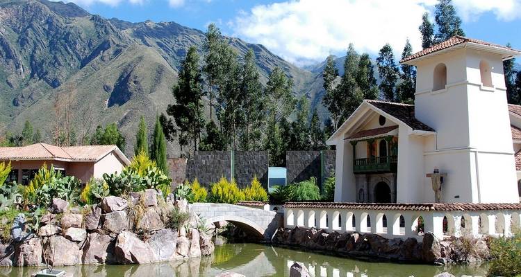Un edificio pintoresco junto a un estanque con montañas al fondo.