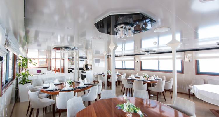 Área de comedor en un yate con mesas elegantemente puestas.