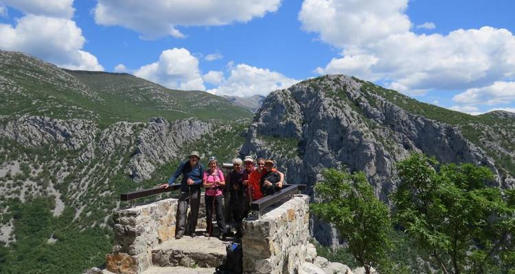 Groupe de personnes posant sur un belvédère en pierre avec des montagnes en arrière-plan.
