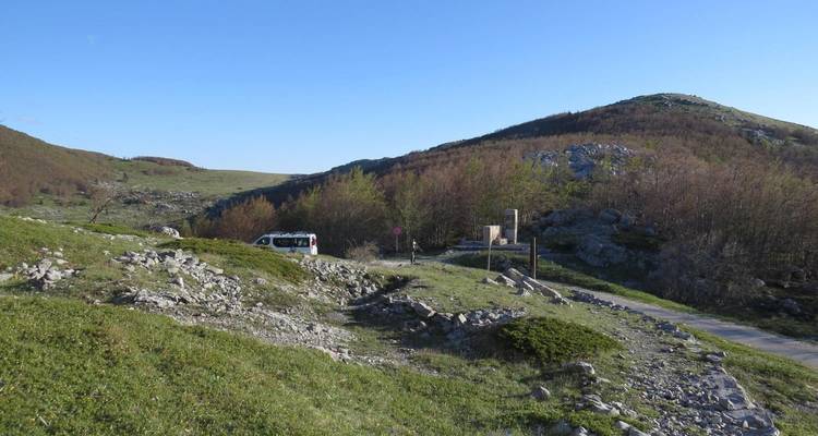 Prairie avec des rochers et un véhicule au loin.