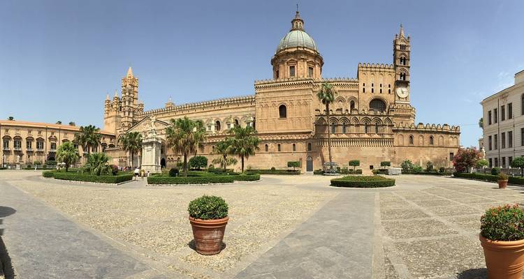 Vista panorámica de la Catedral de Palermo y su plaza rodeada de palmeras en un día despejado.