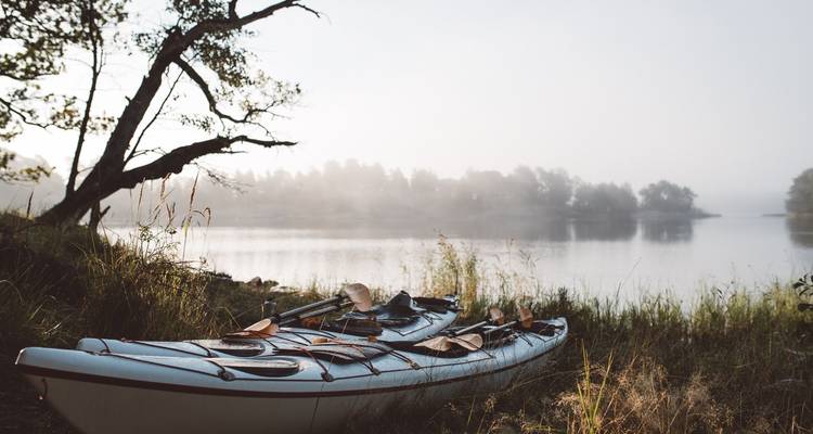 Kayak au repos sur la rive du lac dans un cadre brumeux.