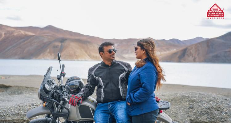 Paar, das mit einem Motorrad an einem See steht, mit einem Wasserzeichen.