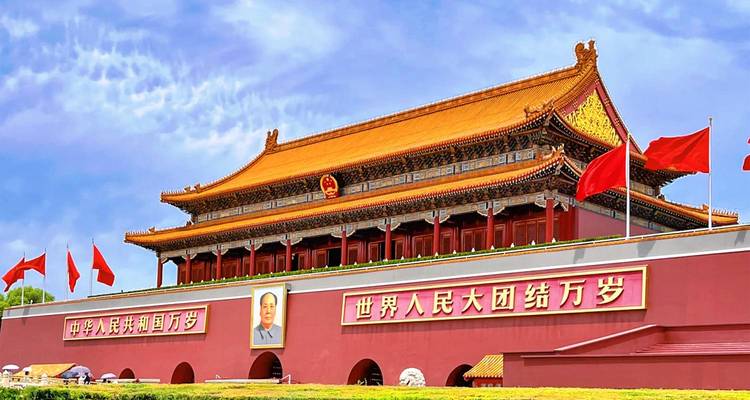 Vista brillante de la Puerta de Tiananmen en Beijing con banderas rojas ondeando bajo un cielo azul vibrante.