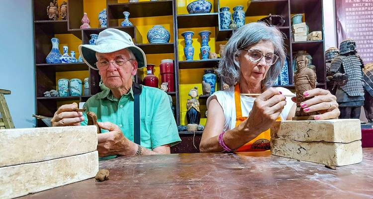 Deux anciens façonnant des figurines d'argile dans un atelier.