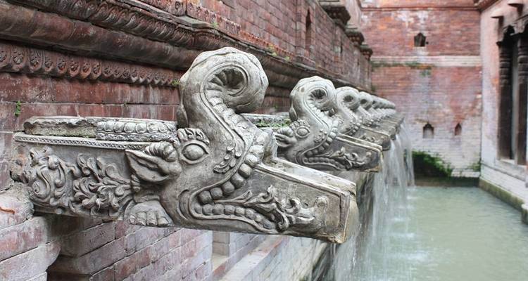 Geschnitzte Steinausgüsse über einem Wasserspiel.