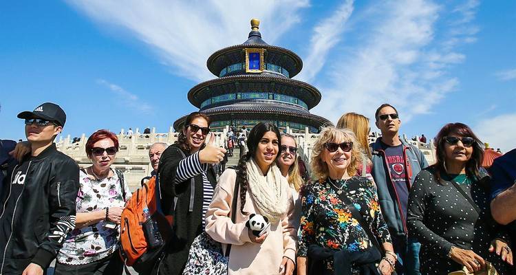 Des touristes posant joyeusement devant le Temple du Ciel de Pékin par une belle journée avec un ciel bleu.