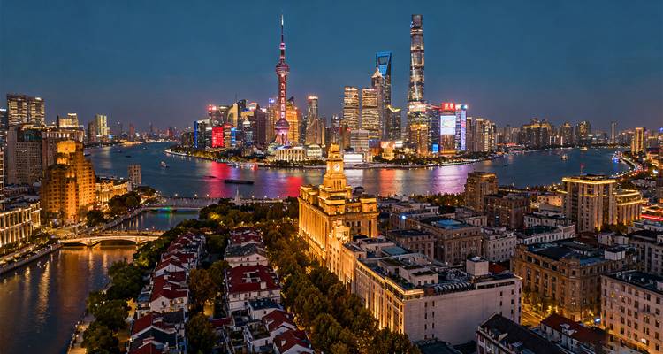 Panoramisch avondlicht uitzicht op de skyline van Shanghai van boven de Bund met gloeiende stadslichten die zich spiegelen in de Huangpu River.