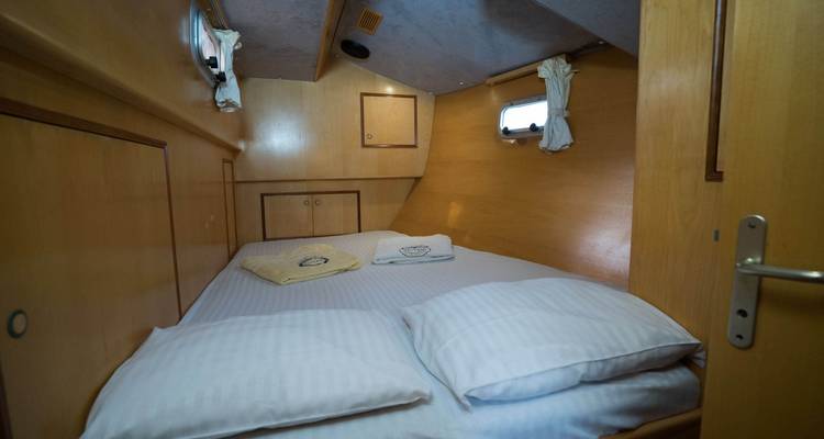 Camarote con cama y ventana pequeña en un yate.