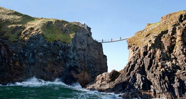 Puente colgante que atraviesa acantilados escarpados sobre el océano.