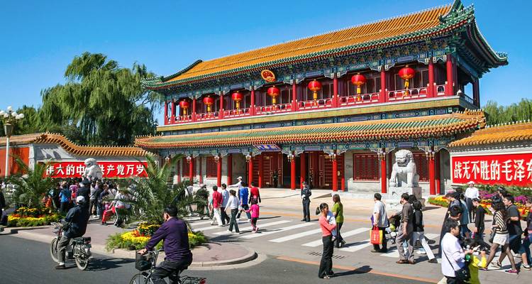 People walking by a vibrant traditional Chinese building.