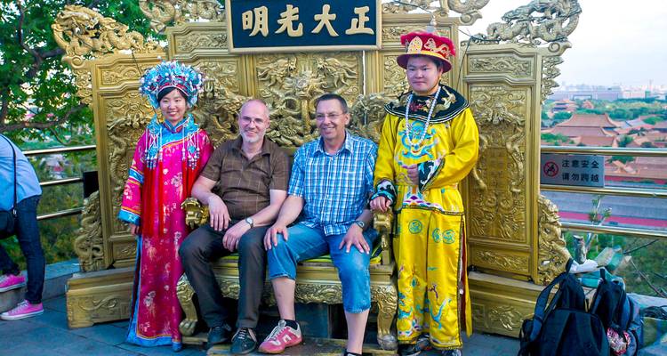 Two men with people in traditional clothing sitting on a throne.