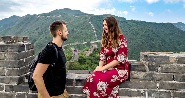 Couple sitting on the Great Wall enjoying the view.