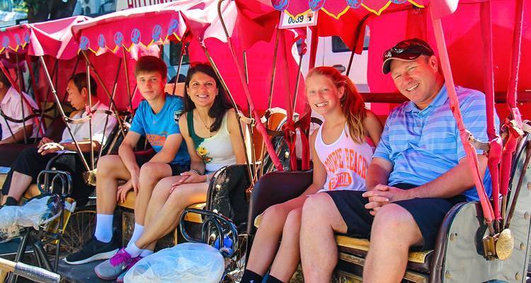 Family enjoying a rickshaw ride on a sunny day.
