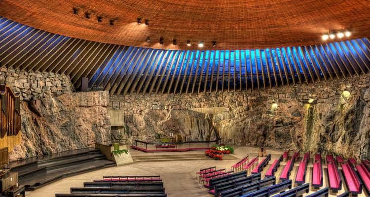 Rock church interior with wooden ceiling and seating.