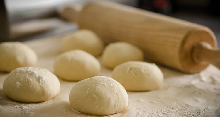 Bolas de masa sobre una superficie enharinada con un rodillo.