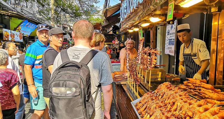 Straßenimbiss-Markt mit Spießen und Touristen, die erkunden.