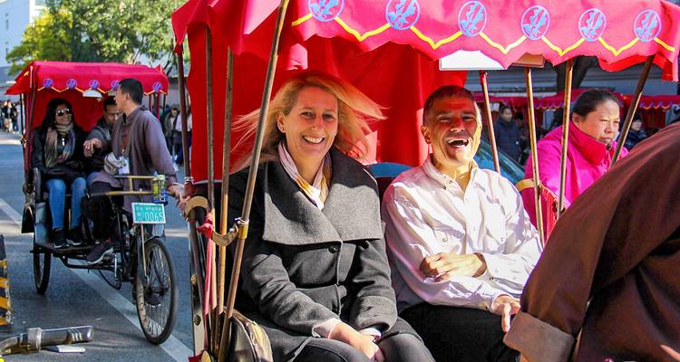 Zwei Menschen genießen eine Rikscha-Fahrt unter bunten Überdachungen.