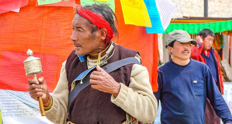 Man die een gebedsmolen vasthoudt op een levendige marktplaats.