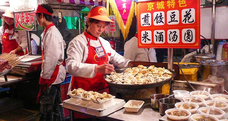 Straatvoedselverkoper die dumplings serveert op een voedselmarkt.