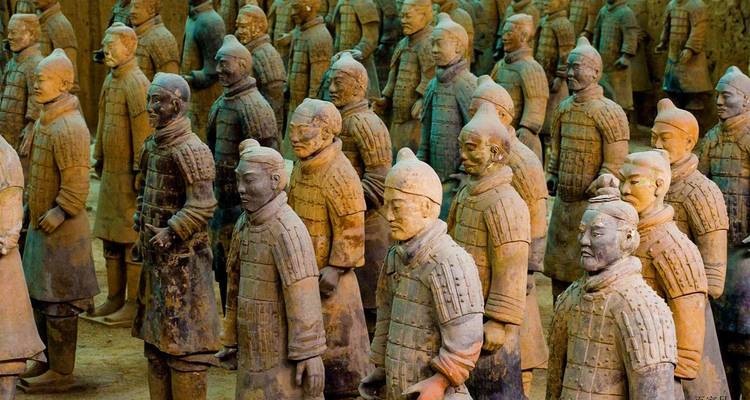 Rows of life-size Terracotta Warriors stand in excavation pit showcasing ancient Chinese craftsmanship.