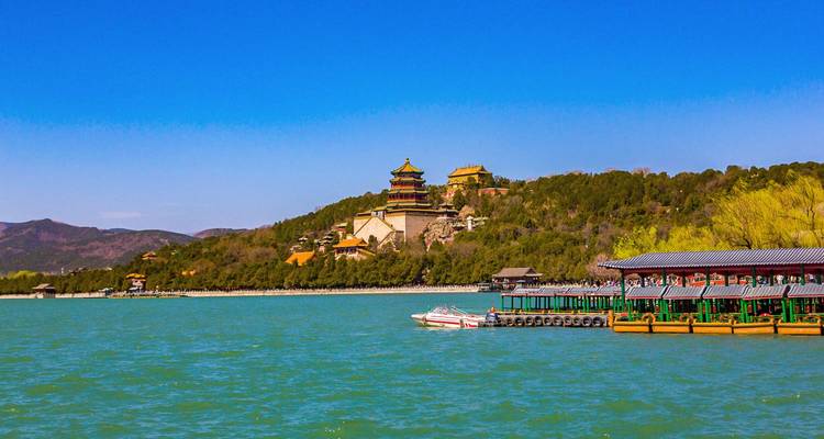 Turquoise Kunming Lake with Summer Palace temples atop forested Longevity Hill under clear blue sky.