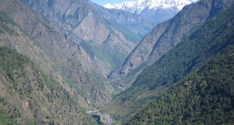 Tiefes Tal mit entfernter Siedlung und Berggipfeln.