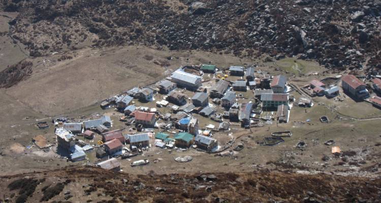 Luftaufnahme eines kleinen Dorfes mit unwegsamem Gelände.