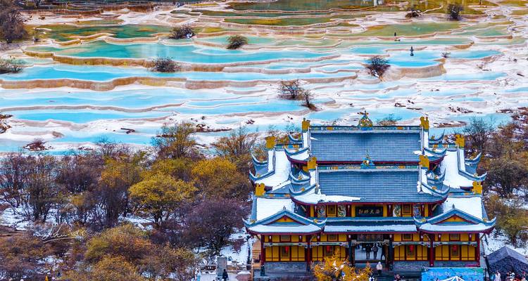 Snow-dusted Daoist temple overlooking Huanglong’s terraced calcite pools filled with turquoise water.