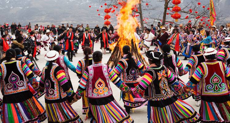 Vibrant ethnic dance circle in colorful traditional attire celebrating around a blazing bonfire.
