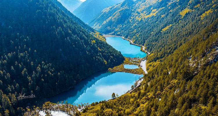Aerial view of two sapphire alpine lakes surrounded by dense conifer forests in Jiuzhaigou.