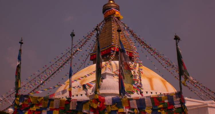 Una estupa con banderas de oración coloridas contra un cielo rojo.