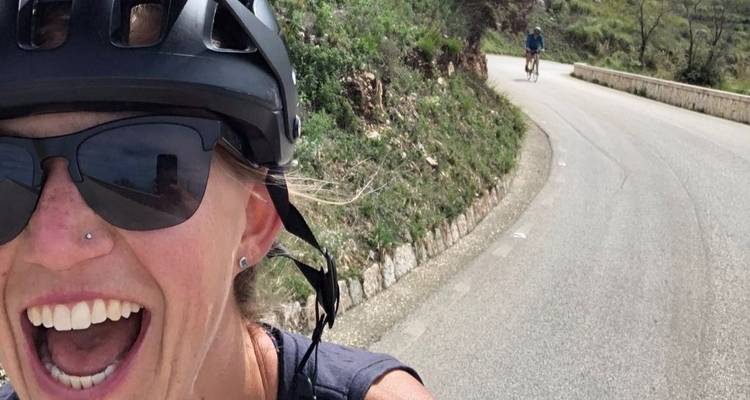 Radfahrer macht ein Selfie mit einer Straße und einem anderen Radfahrer im Hintergrund.