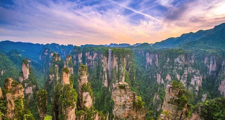 Epic panorama of Zhangjiajie's sandstone pillars beneath a colourful sunset sky