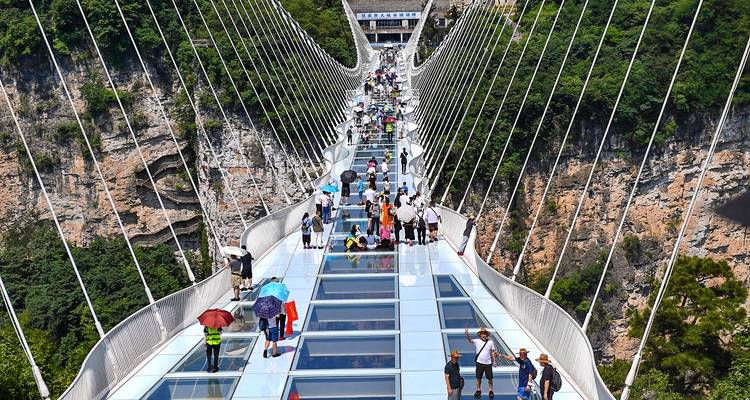 Crowds walk across the famous Zhangjiajie Glass Bridge suspended over a deep gorge