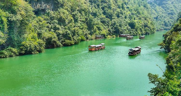Emerald green river winding through forested canyon with small tourist boats