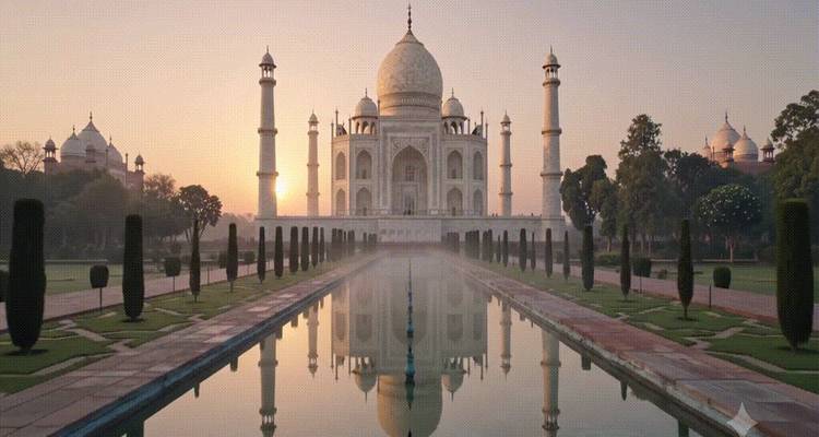 Vista del amanecer del Taj Mahal reflejándose simétricamente en su largo espejo de agua con la luz cálida de la madrugada.