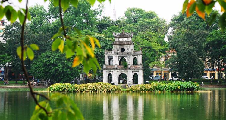 Turtle Tower on Hoàn Kiếm Lake surrounded by lush greenery.