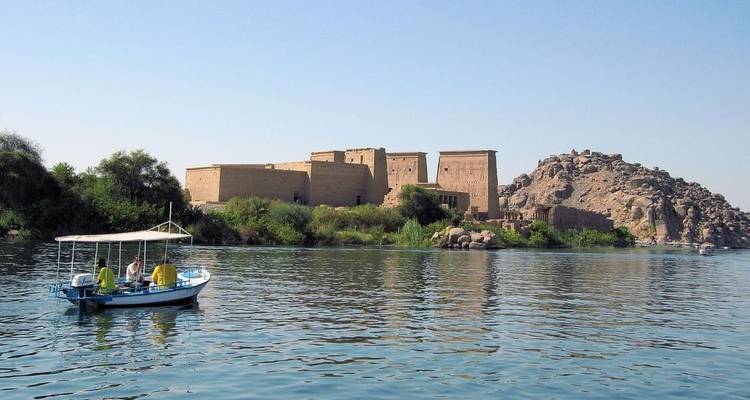 Des touristes dans un bateau sur une rivière avec un temple antique sur la rive.