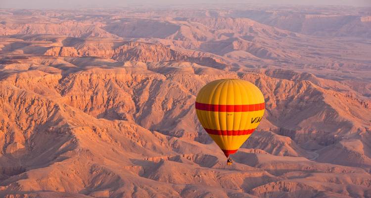 Ein Heißluftballon, der über eine Wüstenlandschaft schwebt.