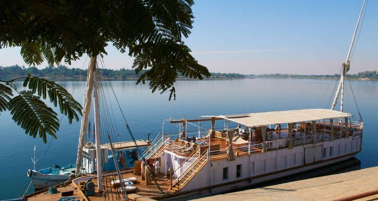 Angedockte Boote auf dem Nil mit üppigem Grün im Hintergrund.