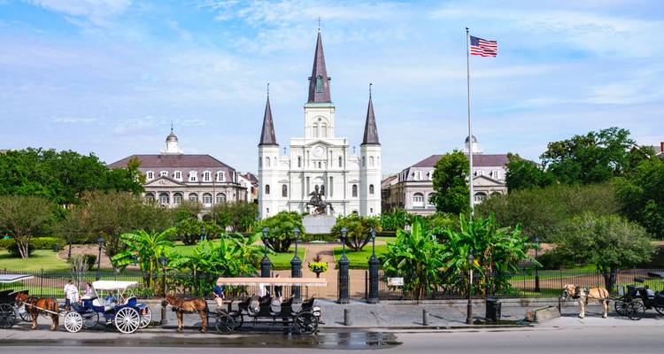 La Catedral de San Luis y la Plaza Jackson con carruajes tirados por caballos y jardines exuberantes en Nueva Orleans.