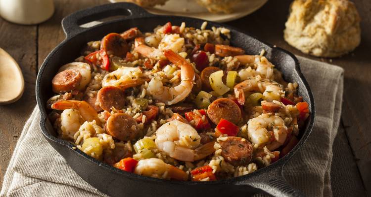 Close-up of a cast-iron skillet filled with hearty jambalaya of shrimp, sausage, rice and vegetables.