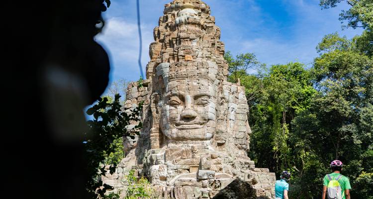 Large stone face on an ancient temple structure in the jungle.