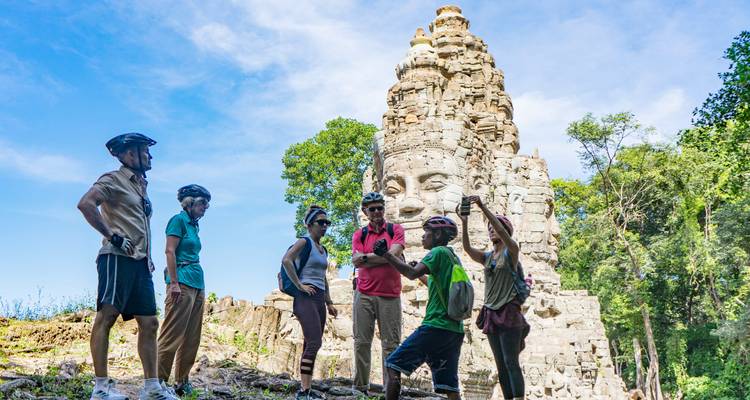 Tourists standing near a large stone face on a temple.