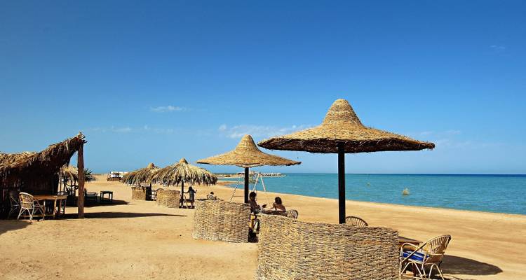 Ruhige Strandszene mit Strohsonnenschirmen am Meer.
